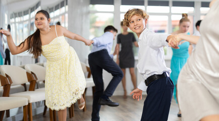 Positive teen boy and girl are dancing contemporary modern discofox in couple during lesson at studio. Leisure activities and hobby for positive people.