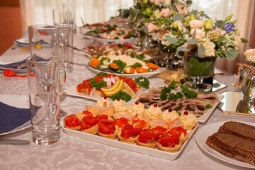 The banquet is festive, beautiful table setting, a table with very tasty meat and fish dishes.
