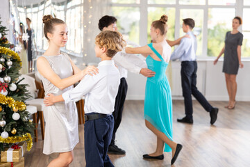 Positive teen boy and girl are dancing classic version of waltz in couple during lesson at studio...