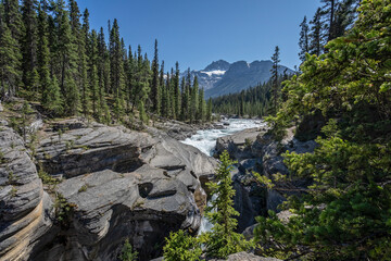 Glacial raging waterfalls in Mistaya Canyon with snow capped mountains in the background in Banff National Park in the Canadian Rockies, - Powered by Adobe