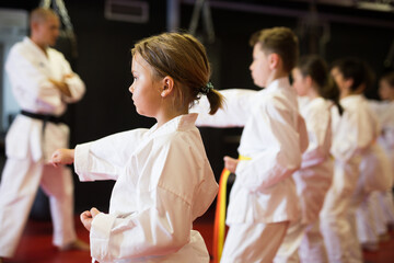 Portrait of girl kid training karate movements in sport class in school
