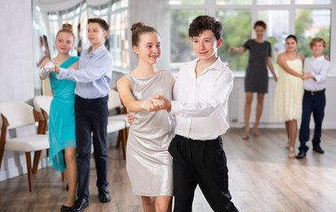 Dancing couples - teenagers in festive clothes dance the Viennese waltz in the dance studio