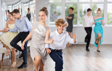 Group of joyful active young dancers practicing in bright dance studio with female instructor in...