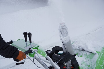 A man cleans snow in the winter in the courtyard of the house,  man cleaning snow with a snow blower