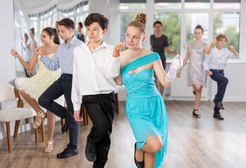 Enthusiastic adolescent partners, girl and boy confidently performing routine in pair in dance studio with group of peers .. - obrazy, fototapety, plakaty