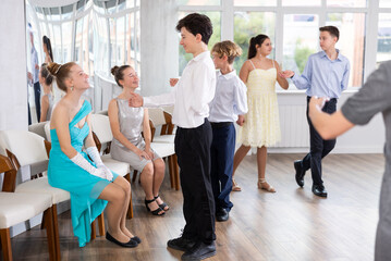 During classical ballroom dancing lesson, boy hold out hand girl and invite her to pair dance.