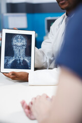 Close up of X ray result on digital tablet in healthcare office. Black doctor holding digital...