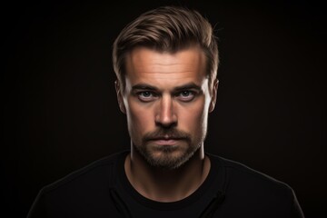 Portrait of a handsome young man with beard and mustache over black background.