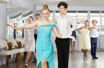 Couple of smiling elegantly dressed young dancers, teenage girl and boy performing curtsy and bow...