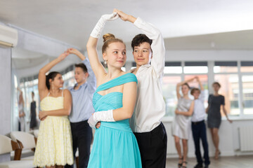 With unhurried music, teen boy and girl in couple spins to rhythm of tango during lesson for novice...