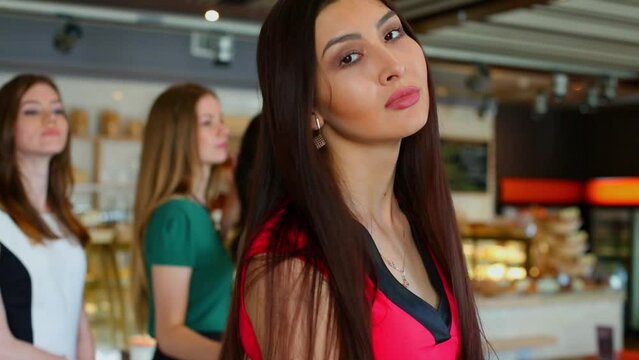 Asian girl with long hairs poses and playmates smile at behind in cafe