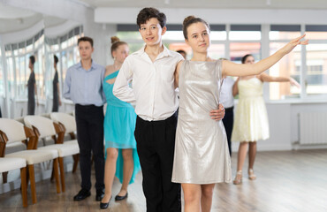 Boy and girl rehearsing social couples ballroom dance in studio