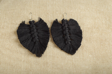 Earrings made with thread on a textile background. Handmade earrings.