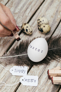 Person stamping 'Easter' on egg with tags 'Happy Eggs'