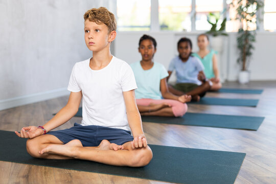 Children together making yoga meditation in lotus pose in modern fitness studio