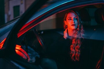 Chica joven posando con luces rojas y azules de noche