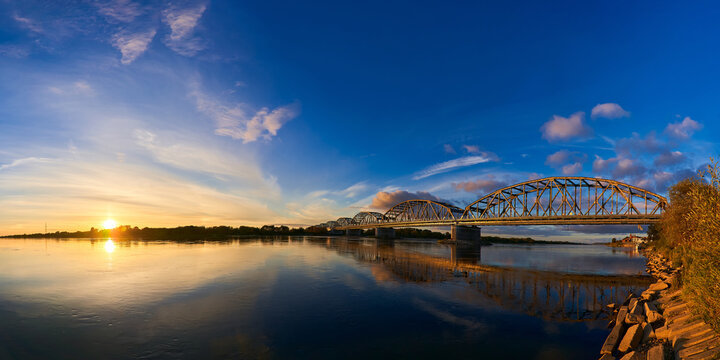 Panoramic photo with a long railway bridge during sunset