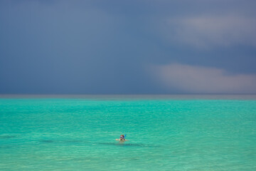 Fototapeta na wymiar A person snorkelling in Caribbean sea during rain. Beautiful tropical colours. 