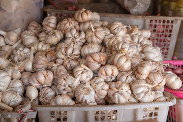 Pile of garlic on a basket, displayed in traditional market stall.