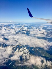 Aerial view of snow covered mountain top from airplane window with airplane wing  