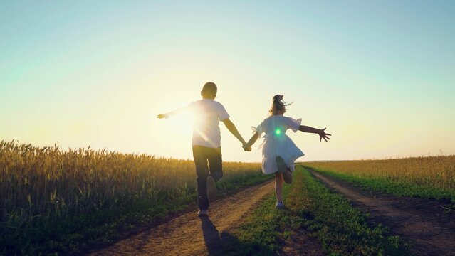 Children play fun run holding hands. Child, nature vacation. Childhood dream concept, Carefree child in summer. Children in together run through wheat field at sunset. Happy family. Boy girl playing