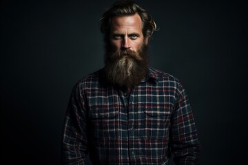 handsome bearded man with long beard and mustache on serious face in checkered shirt on grey studio background