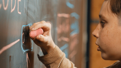 Panorama shot of smart boy writing engineering prompt on blackboard. Attractive student planing a...