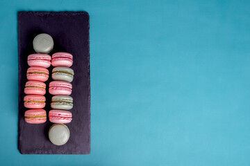 Close up colorful macarons dessert with vintage pastel tones on black stone board.