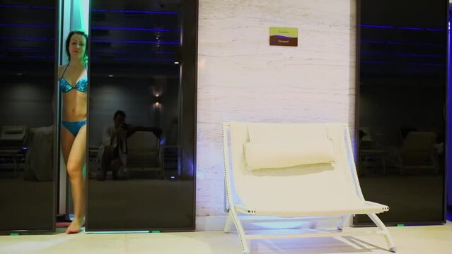 Woman in swimsuit walks out from solarium and lies. photographer reflection