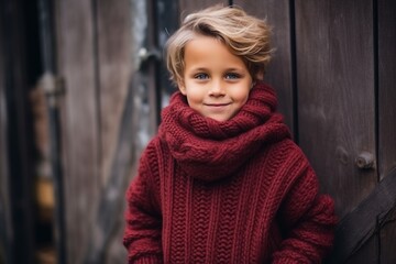 Portrait of a cute little boy in a red knitted sweater and scarf