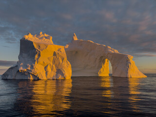 A huge high breakaway glacier drifts in the southern ocean off the coast of Antarctica at sunset,...