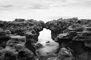 Dramatic monochrome seascape with natural rock arch, perfect for artistic photography and stark, nature-inspired designs.