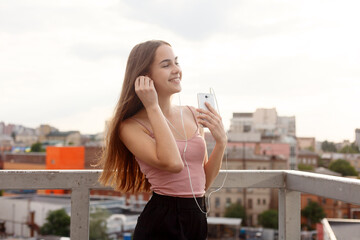 Young woman with headphones dangling on her mobile phone