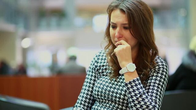 Sad young woman cries and looks around in hall of trade center