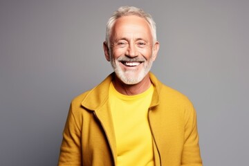 Portrait of a smiling senior man in a yellow jacket. Studio shot.