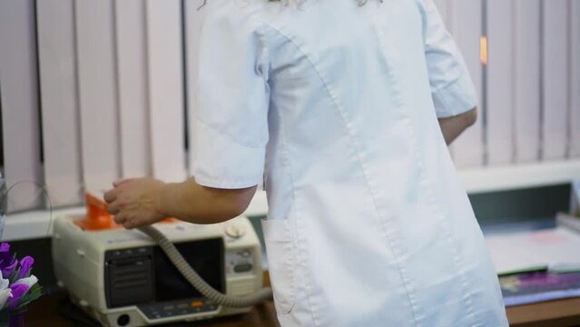 Nurse puts electroconvulsive shock probes back to device in hospital cabinet