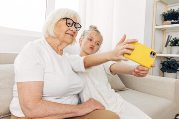 Family grandmother smiling phone hugging bonding selfie togetherness granddaughter child sofa