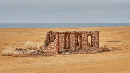 Ruins of an old, brick farmhouse on a cliff in a freshly harvested field - Yorke Peninsula, South...