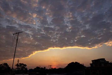 Sunset sky with clouds and silhouette of a building in the city