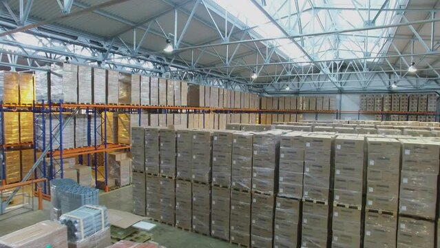 Storehouse with many stacks of boxes on floor and shelves 