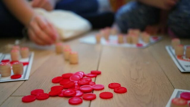 Red chips and barrels for bingo are on parquet floor during kids play