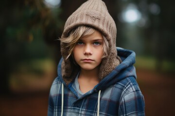 Portrait of a little boy in a plaid shirt and a knitted cap.