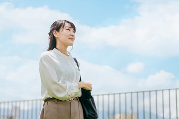 青空を見上げるビジネスウーマン（充実・やる気・キャリア）
