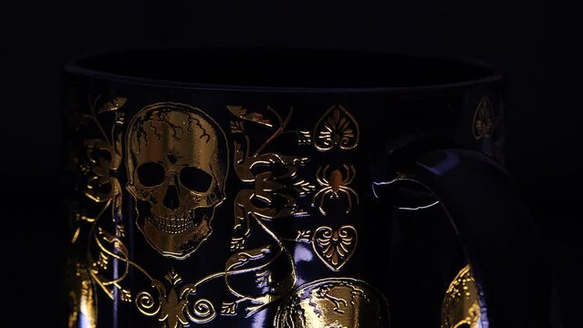 black glass cup with gold skull patterns
