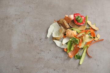 Peels of fresh vegetables on grey textured table, flat lay. Space for text