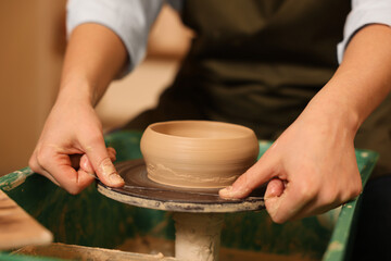 Clay crafting. Woman removing bowl from potter's wheel with thread