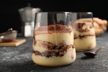 Delicious tiramisu in glasses on grey textured table, closeup