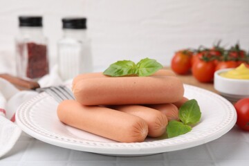 Delicious boiled sausages and basil on white tiled table