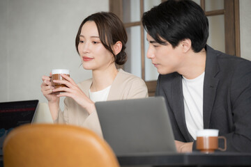 パソコンを使いながら会話する女性（キャリアウーマン）のいるビジネスシーン 打ち合わせやミーティングのイメージ