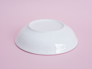upside down white porcelain bowl on pink background. Minimal style.